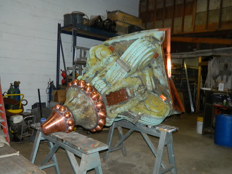 Large copper building ornament mid-restoration with new copper let into the old