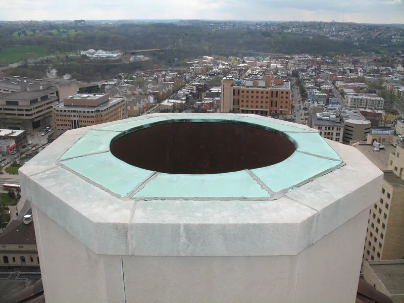 Copper-flashed oculus at the top of a dome drum above Pittsburgh