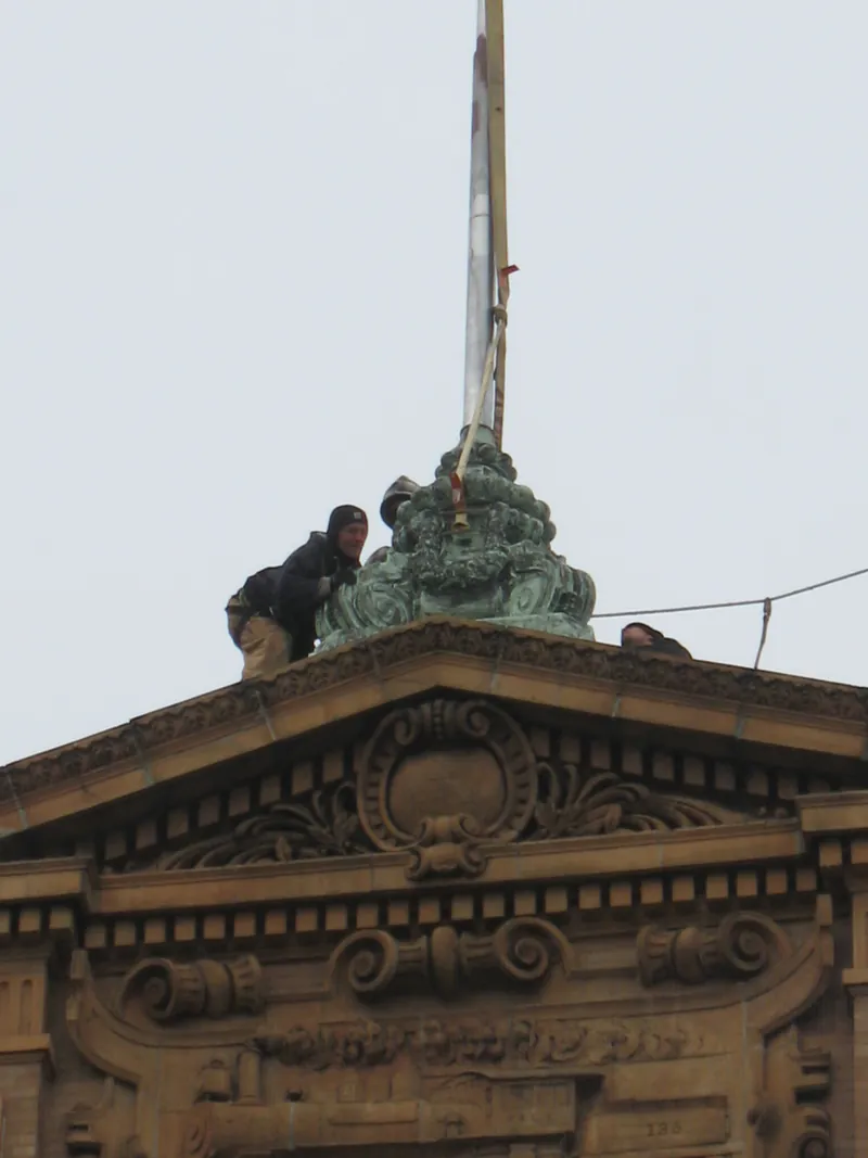 Crew guiding the restored copper ornament onto the building pediment
