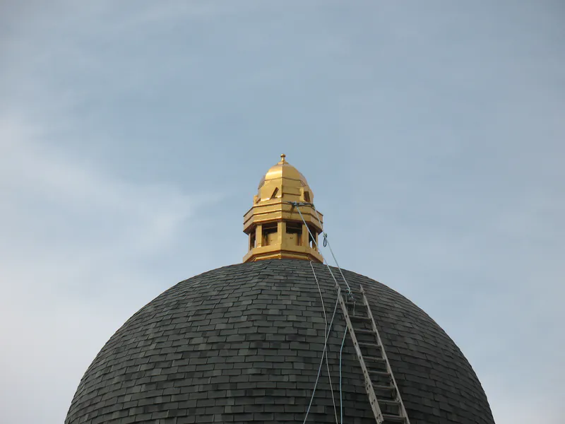 Ladder leaned against a slate dome up to a gilded cupola