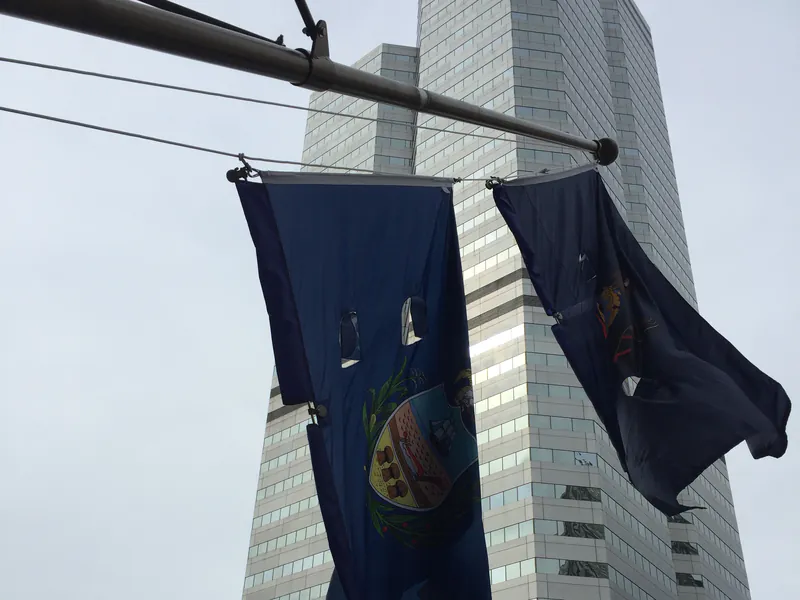 Outrigger-mounted flags high on the City-County Building with a glass tower behind
