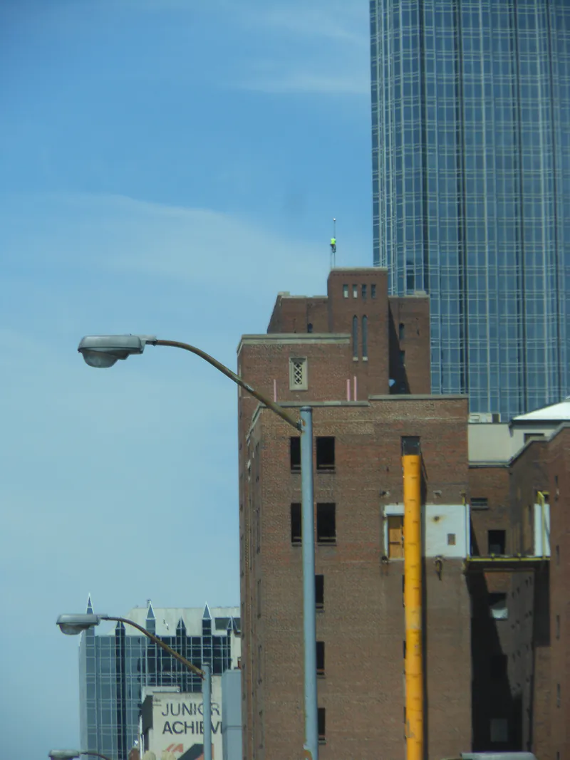 Climber on a rooftop mast high above the downtown Pittsburgh skyline
