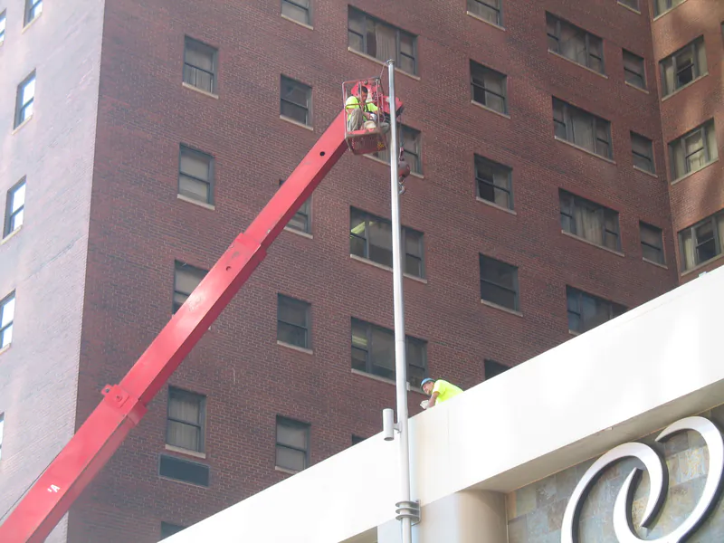 Red boom lift extended up the façade of a downtown hotel tower