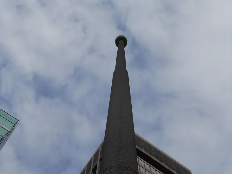 Tall rooftop pole on a downtown high-rise seen from its base