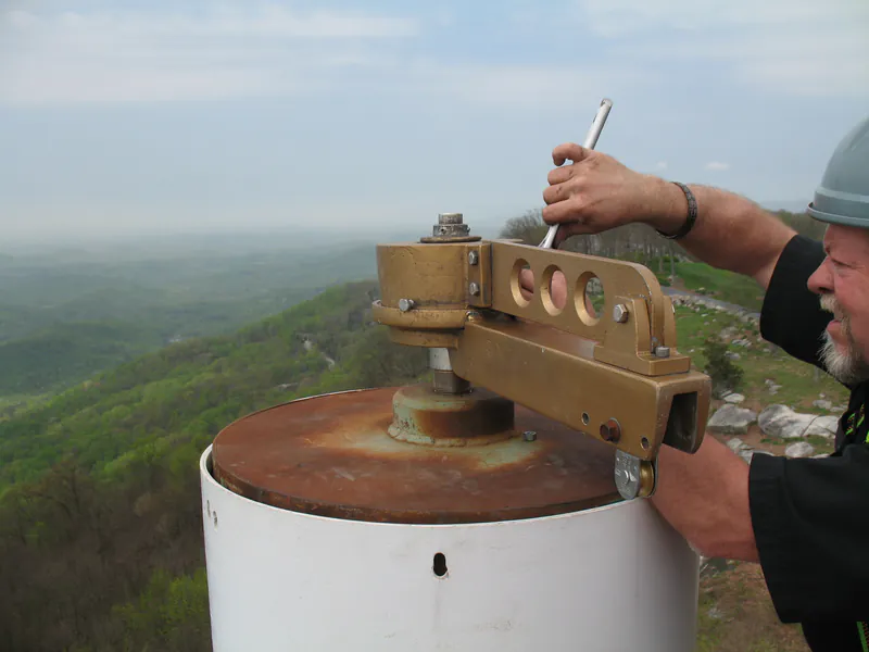 HigherUSA technician servicing a flagpole truck at the top of a pole on a mountain summit