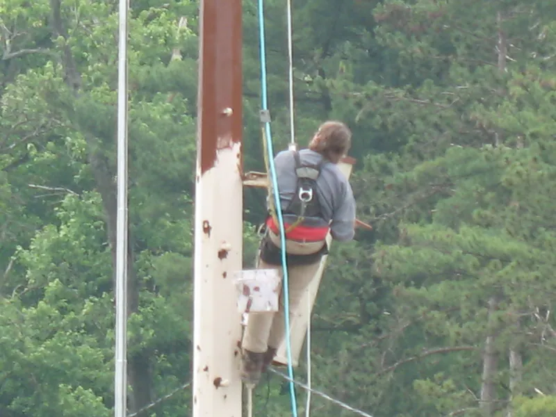 Climber in a full harness tied off on a steel light pole