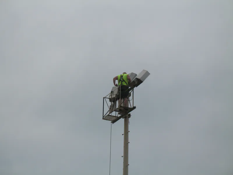 Technician in a pole-top cage working on a light fixture
