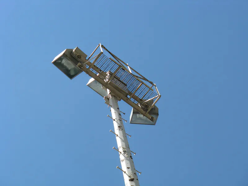 Pole-top service platform and floodlight fixtures against blue sky