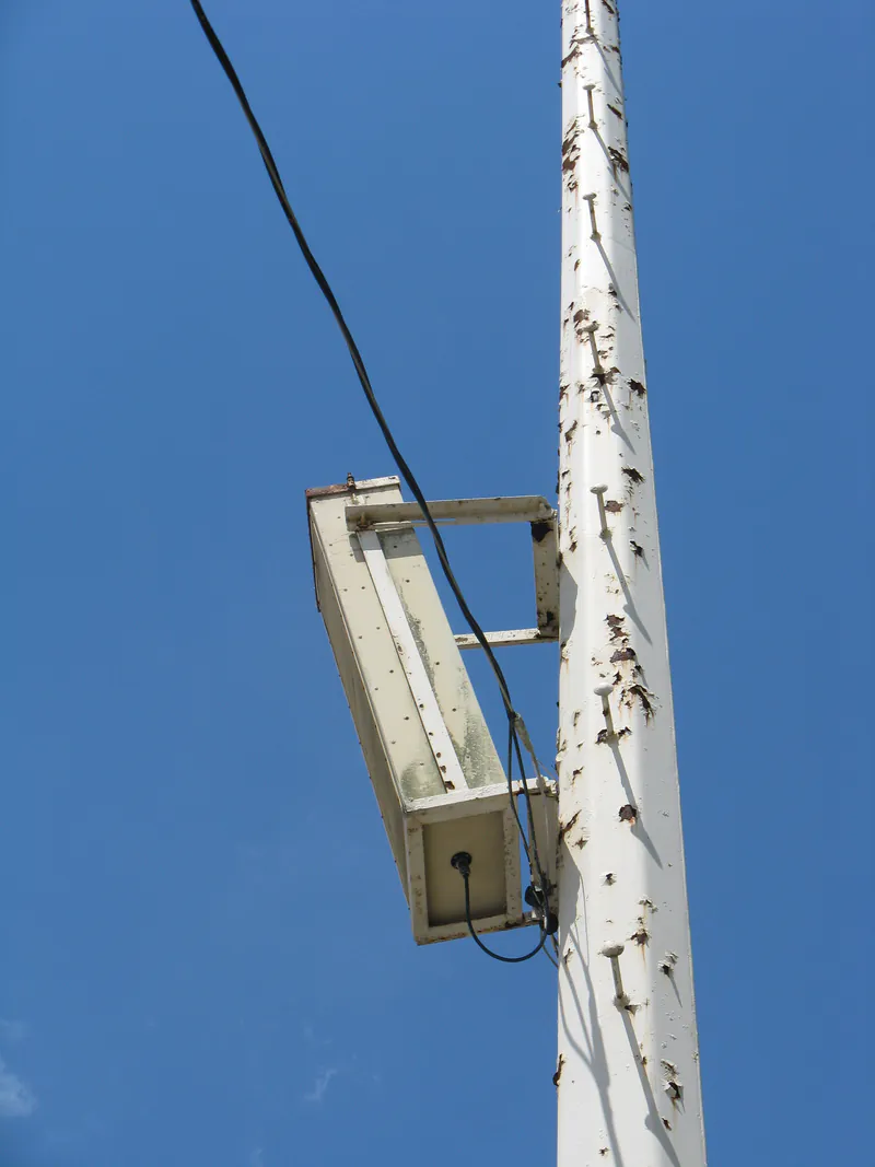Side-mounted floodlight fixture and its feed cable on a light pole
