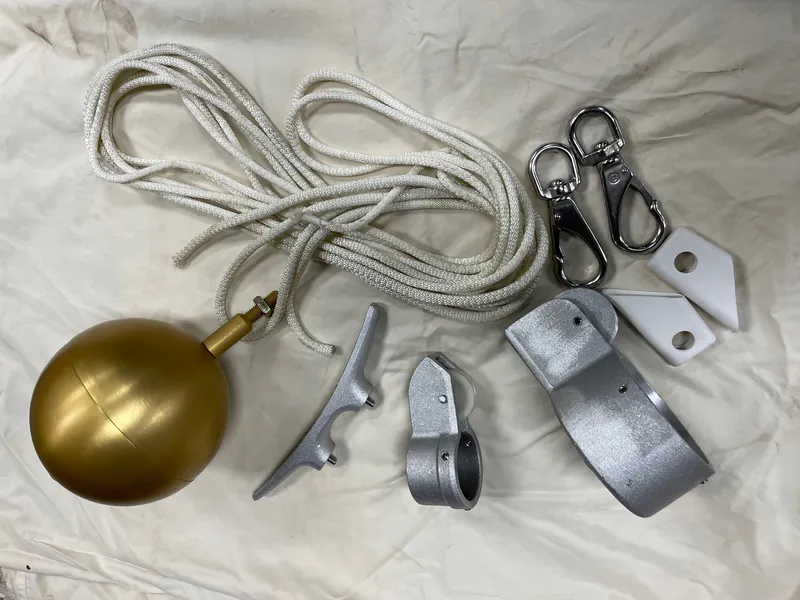 External halyard flagpole components laid out: gold ball, truck, cleats and brackets