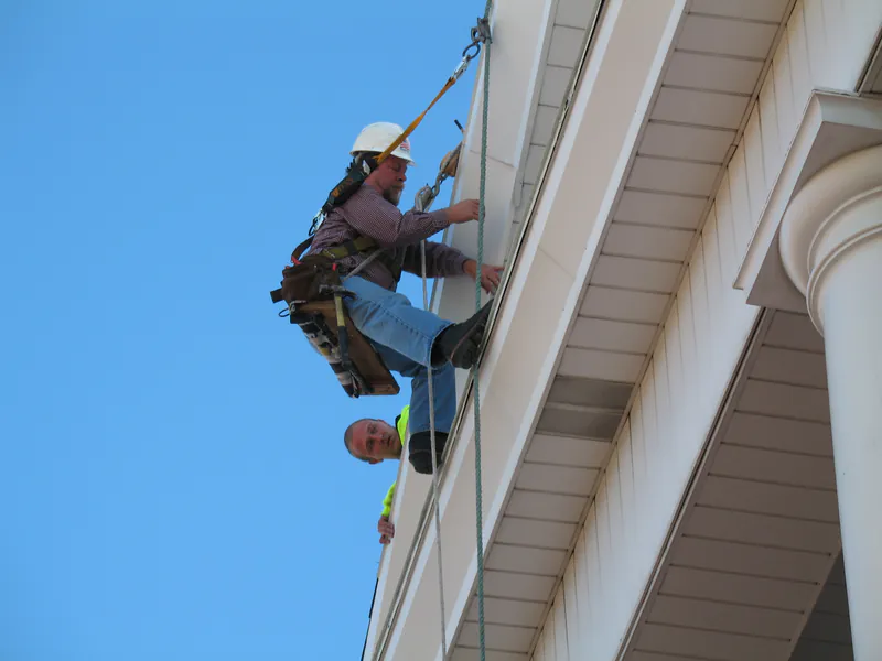 Worker in a bosun's chair over a church cornice