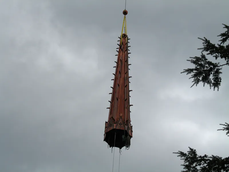 Copper church spire suspended from a crane during removal